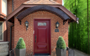 Tinted polycarbonate entryway awning over an elegant front door, offering year-round rain and snow protection with a stylish architectural touch