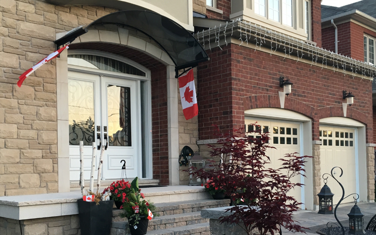 Advantages of Polycarbonate Awnings in Canadian Homes 6 Tinted polycarbonate awning installed over a front door of the canadian contemporary house' entrance with seasonal flags softly mounted on the brackets