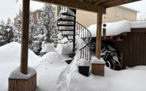 Polycarbonate awning covered in heavy snow in a Canadian backyard, demonstrating its durability in winter weather.