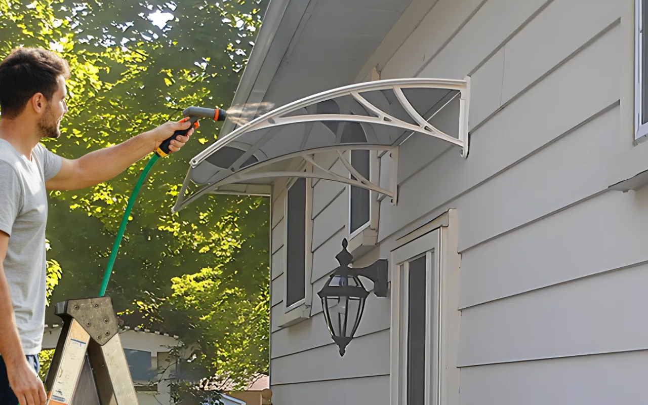 Spring Prep – Get Your Outdoor Awning Ready 8 Polycarbonate awning being rinsed with a garden hose to remove dirt and debris.